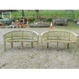 A pair of weathered teak banana shaped garden benches 160 cm wide