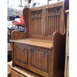 An old English style box settle with carved and panelled back with ecclesiastical style detail,