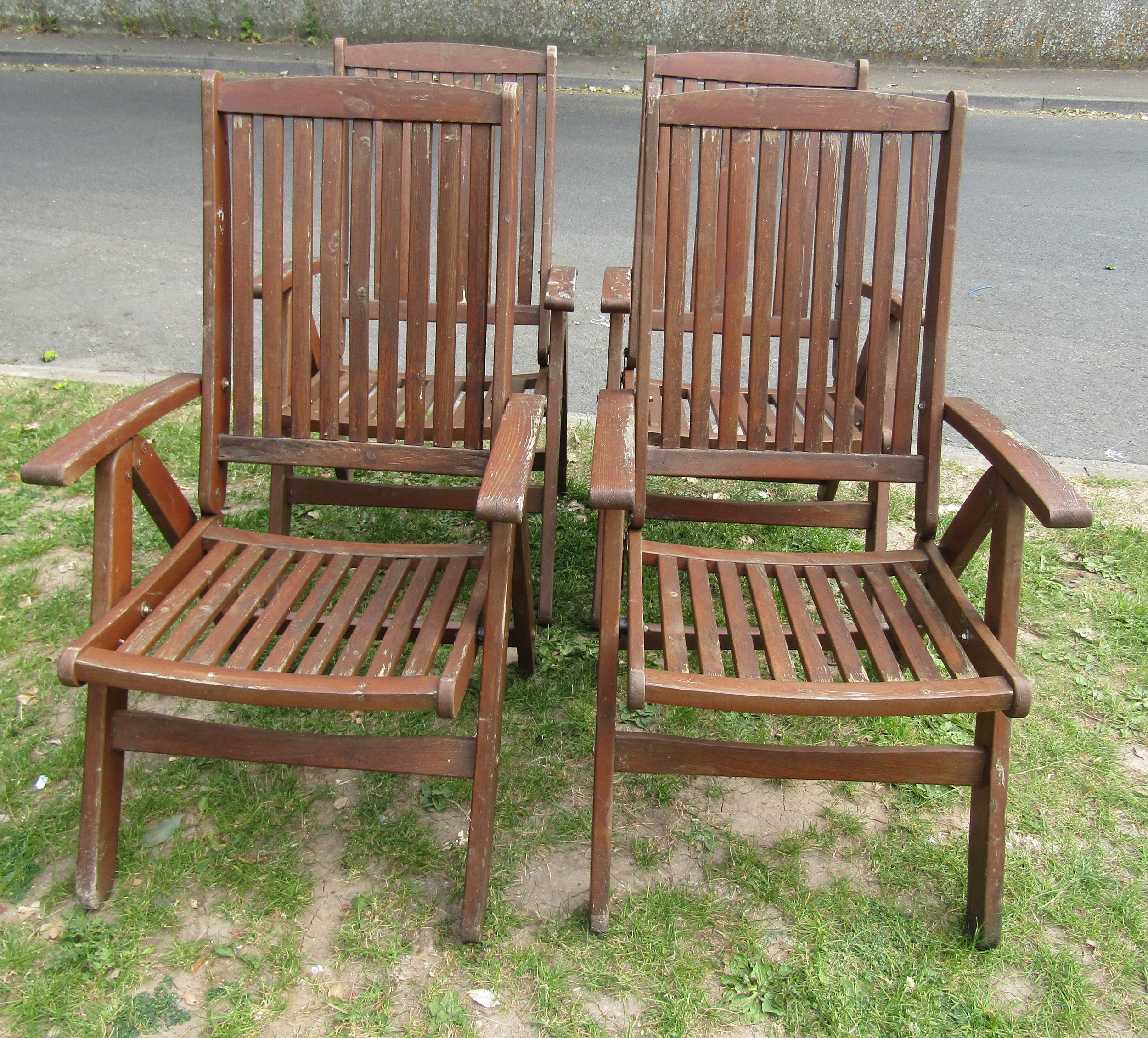 A set of four stained folding softwood garden armchairs with slatted seats and backs, labelled