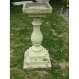 A painted and weathered two sectional bird bath with square top raised on a baluster pedestal with