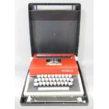 A 1970’s red and cream plastic Petite International de luxe typewriter, in a hard plastic grey carry