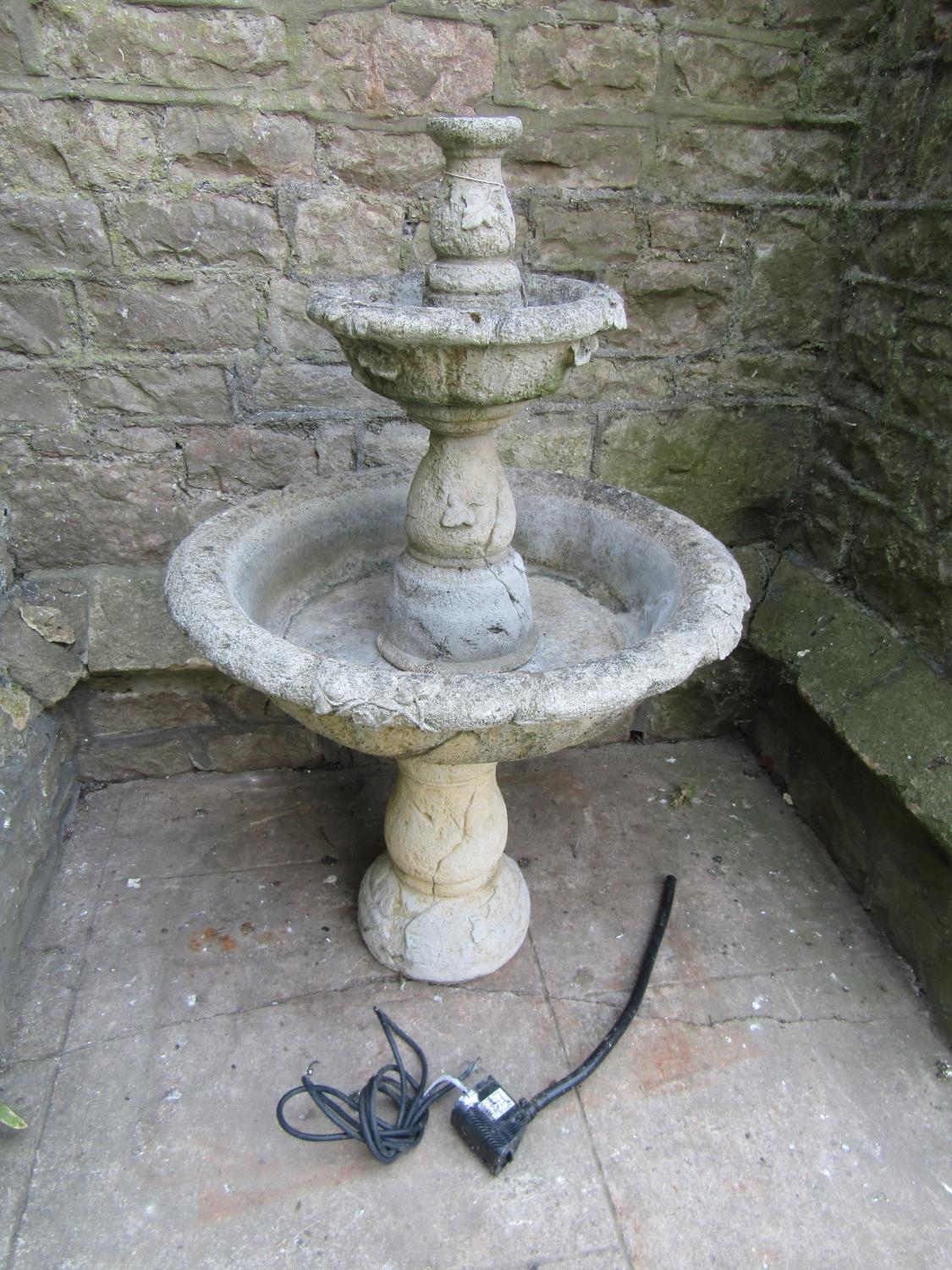 A weathered cast composition stone five sectional garden fountain with simple trailing ivy detail,