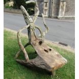 A large weathered rustic sculptural tree root chair with carved trailing vine, tree and bird detail,