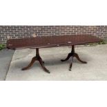 A mahogany veneered twin pedestal dining table, on gun barrel turned base, with lion's paw capping