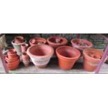 A quantity of terracotta flower pots of varying size and design, some with incised detail, the