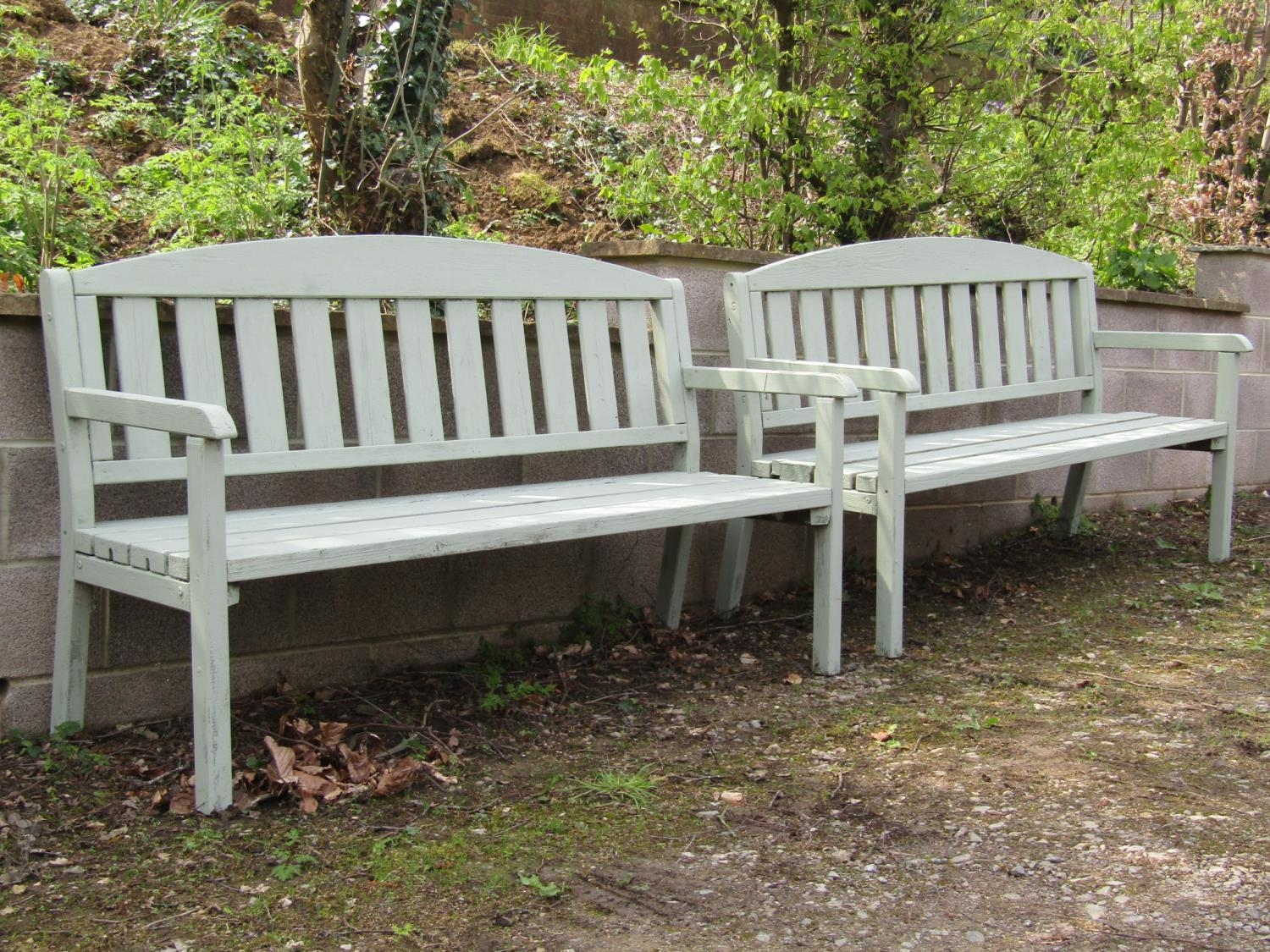 A pair of light green painted soft wood three seat garden benches with slatted seats and backs