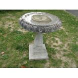 A weathered cast composition stone three sectional bird bath with circular top raised on a