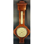 An Edwardian aneroid barometer with carved and crossbanded case with silvered dials