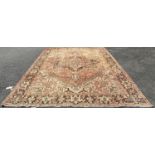 A large faded and slightly worn old Kazak carpet with a central star shaped medallion in pale