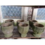 A set of six small weathered cast composition stone circular garden urns with Greek key, fixed