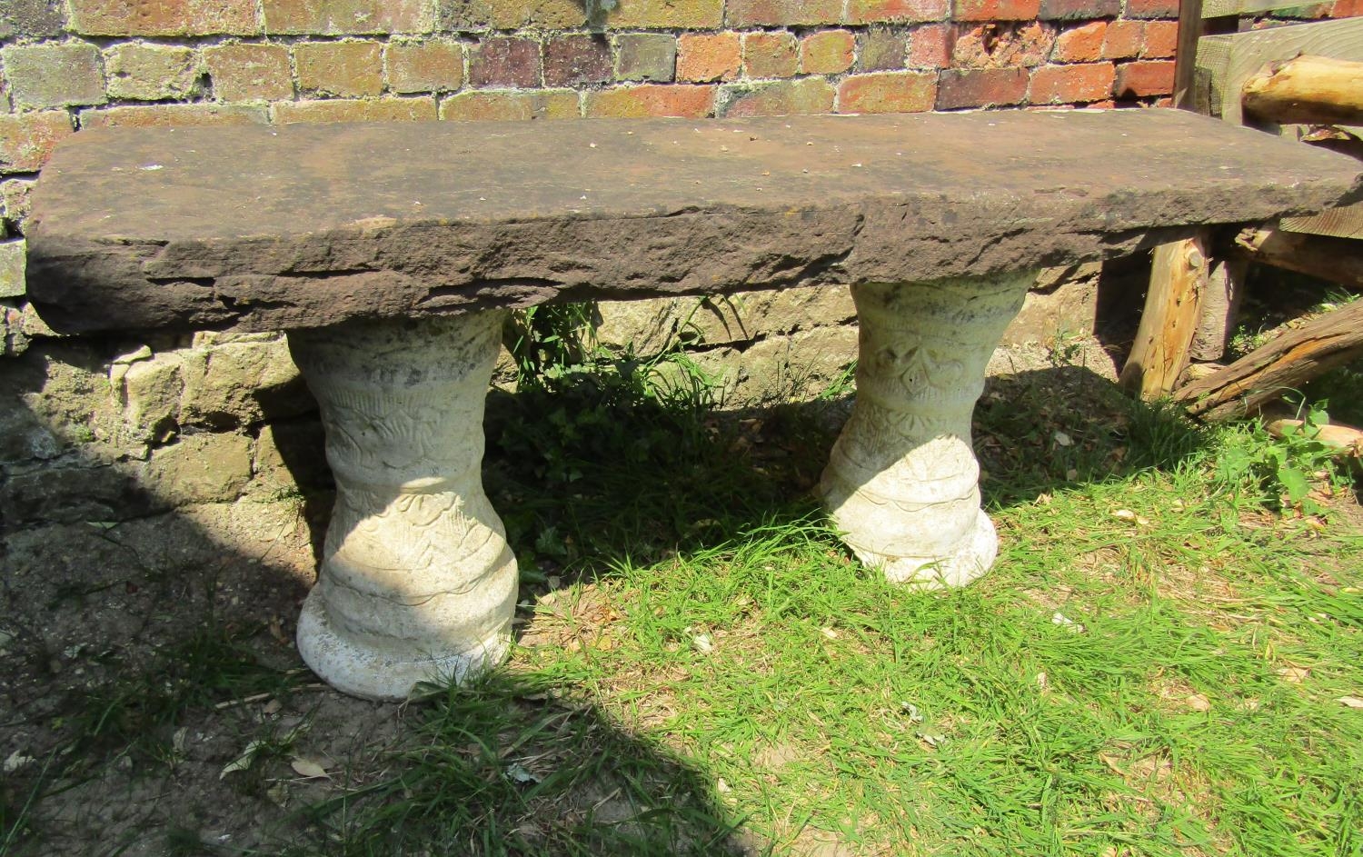 A three sectional garden bench with rectangular thick natural stone top raised on a pair of cast