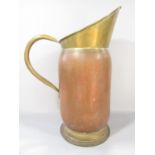 A 19th century brass and copper pitcher with a brass loop handle, 50cm high.