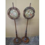 A pair of mid-19th century rosewood pole screens, the circular disc bases supporting circular carved