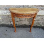 An oak demi-lune side table with carved border and frieze raised on shaped supports with claw and