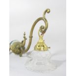 A brass scrolled wall light with a dangling glass shade, and a section of another brass light