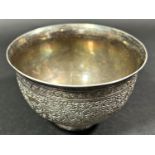 A small Middle Eastern silver metal tea bowl with an intricately incised and engraved flowing floral