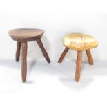 A pine three legged low stool and another stool constructed from natural oak raised on three natural