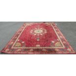 A large Wilton type carpet with a Persian design of a central medallion on a field of flowers on a
