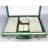 A mahjong game with bone and bamboo tiles in a green silk lined carry case.