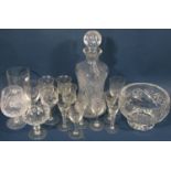 A collection of glassware including a tall narrow cut glass vase, three various decanters, a fruit