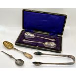 A pair of silver spoons with scalloped bowl in case, a small berry spoon and a silver plated sugar