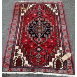 A Kazak design rug with a central stepped medallion on a red and green ground (stained in one