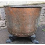 An antique copper with rolled rim and pop riveted seams, raised on later cast iron swept feet,