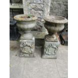 A pair weathered cast composition stone garden urns with circular lobed bowls and fixed socles,