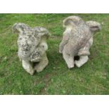 A matched pair of weathered cast composition stone garden ornaments in the form of seated