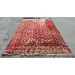 A large Persian style carpet with multi-geometric pattern on a red ground (faded in places) 340 cm x