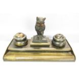 An early 20th century brass pen and ink stand with a central owl with amber eyes, perched on books