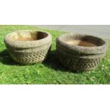 A pair of weathered cast composition stone garden planters in the form of lattice baskets of squat
