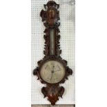 A substantial Victorian aneroid barometer with silvered dial, the oak case carved with acanthus