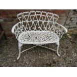 A small painted cast alloy garden bench with decorative pierced repeating open scroll pattern,