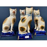 Two pairs of Staffordshire cats upon blue cushions, a further pair of Staffordshire poodles with