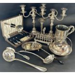 A pair of Georgian style silver plate three sconce candlesticks, two ladles, serving spoons, toast