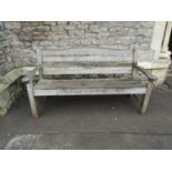 A Swan Hattersley weathered teak three seat garden bench with slatted seat and back beneath a curved