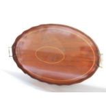 An early 20th century oval mahogany tray with a raise wavy edge and two brass handles, 63cm x 42cm.