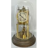 A brass cased anniversary or 100 day clock with silvered dial, column supports and set beneath a