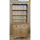 A stripped pine cottage kitchen dresser, the base enclosed by a pair of rectangular panelled doors