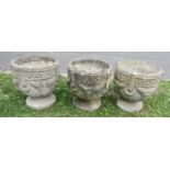 A set of three weathered cast composition stone circular garden urns with repeating Greek key, fixed
