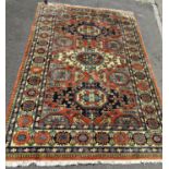 A Kazak Rug with three central diamonds in a field of burnt orange with repeating patterned