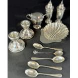 A scalloped shell dish, a pair of squat silver candlesticks, five assorted small spoons, and a three