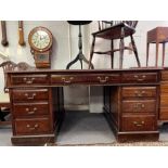 An Edwardian mahogany pedestal writing desk with nine drawers, inset maroon leather top within a