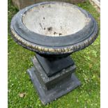 A cast composition stone garden urn with flared rim, lobed body and fixed socle raised on a squat