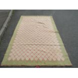 A wool trellis patterned rug in pistachio and pink tones on a natural wool ground, 250 x 160 cm