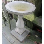 A three sectional cast composition stone bird bath with circular top, raised on a baluster