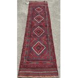 A Meshwani Runner with a central row of diamond meddling in tones of red and blue, 254 x 64cm approx