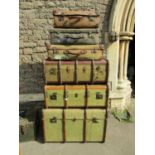 A stack of vintage luggage including timber banded examples an old green painted box and a timber