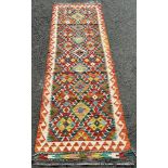 A Chobi Kilim runner with three rows of alternating stepped and diamond medallions 250 x 75cm